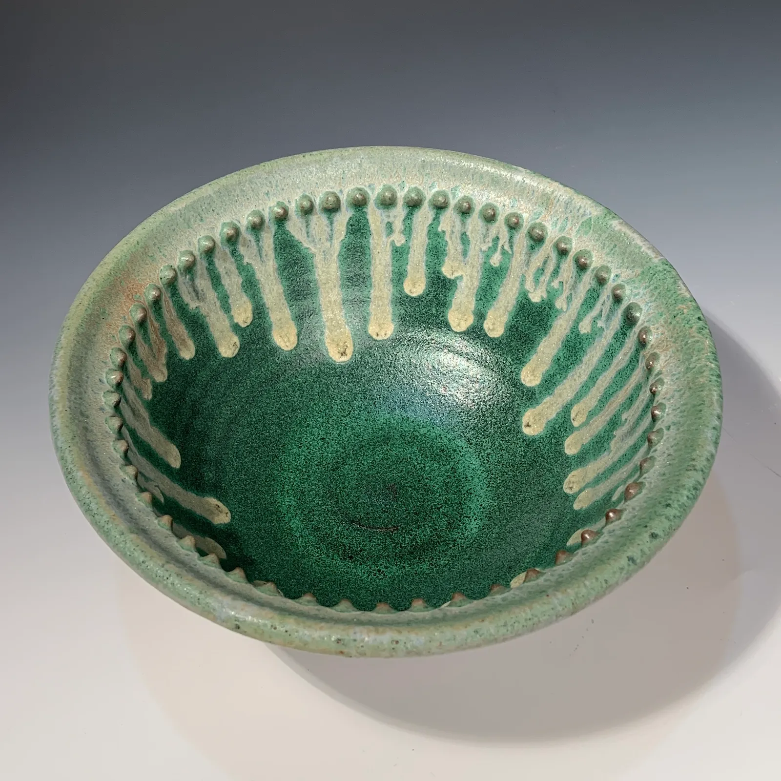 Juniper bowl seen from above, deep green with cream drips running down from a beaded inner rim.