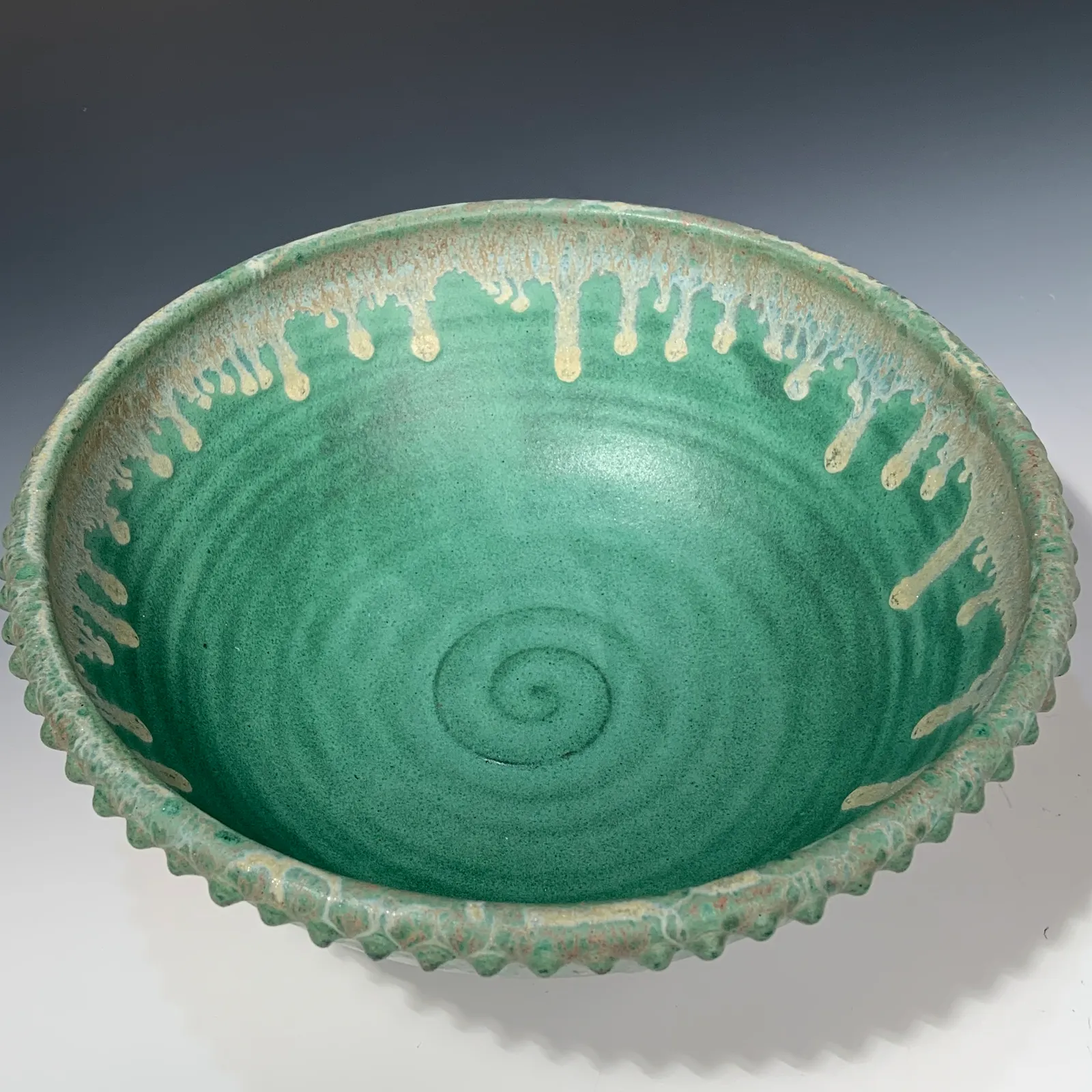 Large Juniper bowl in matte jade green with a spiral at the center and a scalloped, beaded rim.